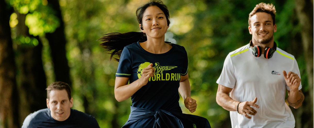 Kolme Wings for Life World Run -juoksutapahtuman osallistujaa juoksemassa iloisena Philips-urheilukuulokkeet päässä.